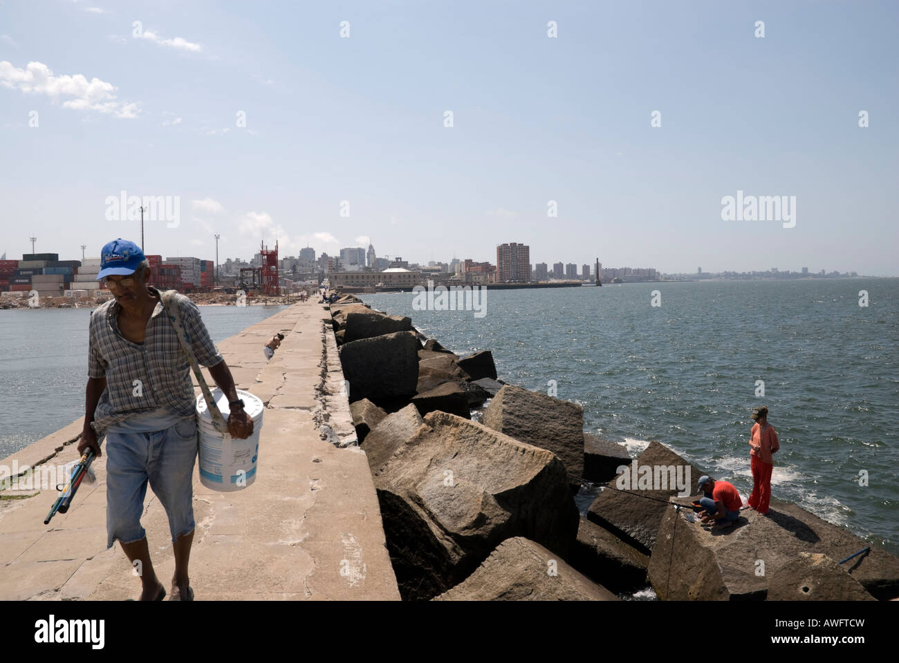 Vieux Pêcheur marchant dans un pilier de béton à Montevideo, Uruguay. Banque D'Images