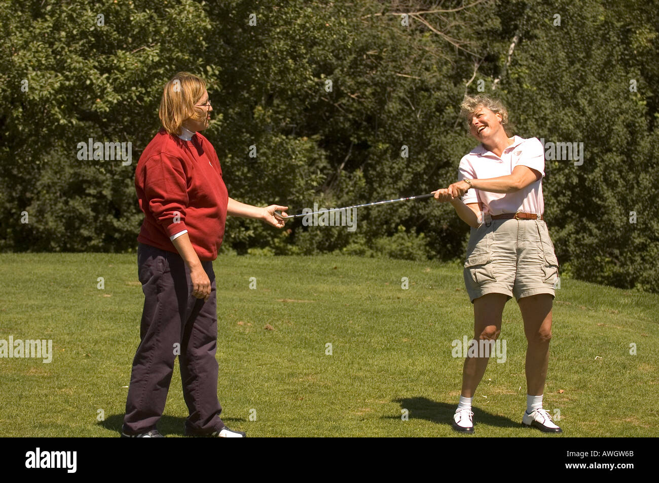 Une femme rit tout en obtenant une leçon de son professionnel de golf. Banque D'Images