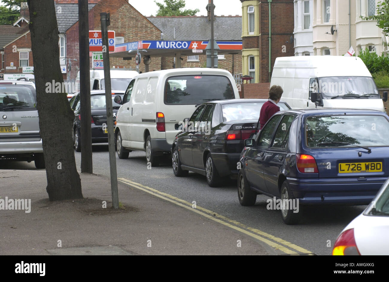Une femme crooses la route à travers un lourd d'attente de trafic causé par voie de bus fonctionne sur l'A6 à Bedford UK Banque D'Images