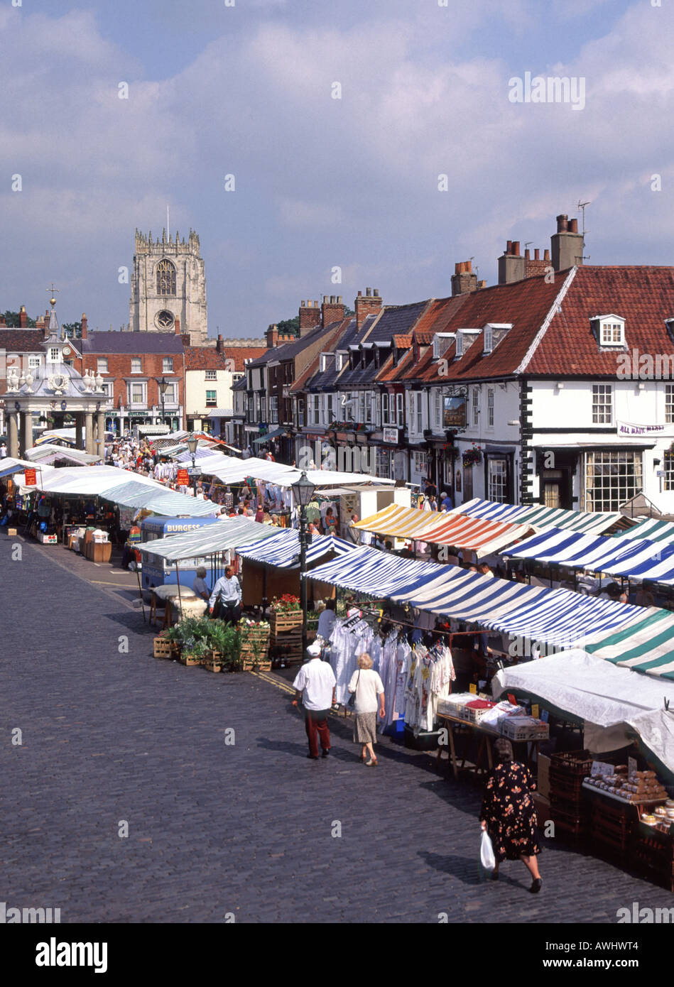 En regardant les gens sur place du marché avec des stands et des canopies historique marché croix et église tour Beverley Market ville East Yorkshire Angleterre Royaume-Uni Banque D'Images