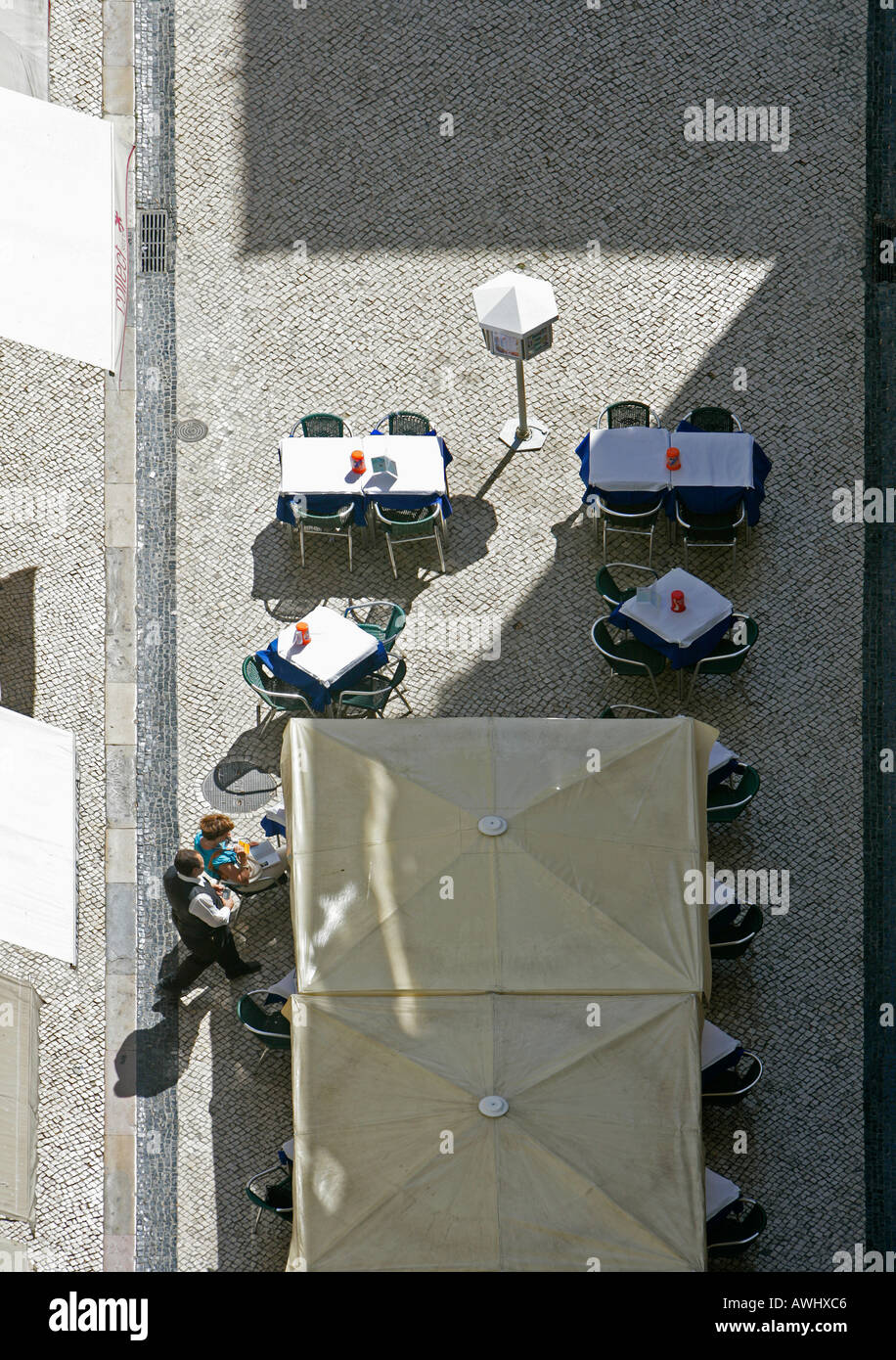 Un café en plein air dans une rue piétonne pavée avec un client et un serveur comme vu d'en haut dans le quartier de Baixa Lisbonne Banque D'Images