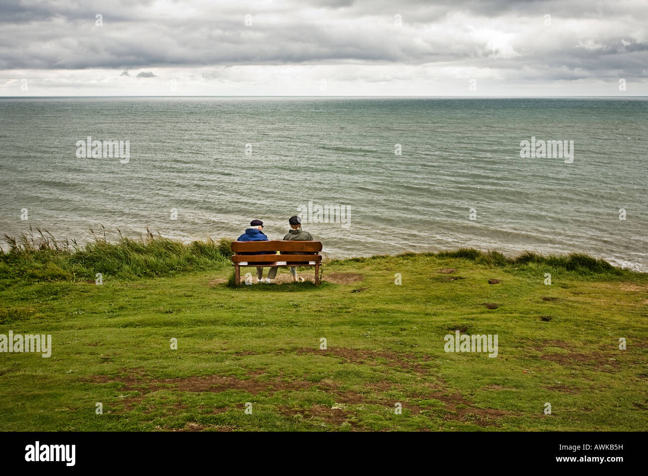 Couple assis sur le banc en bois face à la mer en automne / hiver Banque D'Images