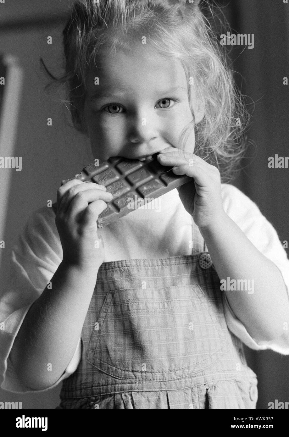 Girl eating chocolate bar, b&w Banque D'Images