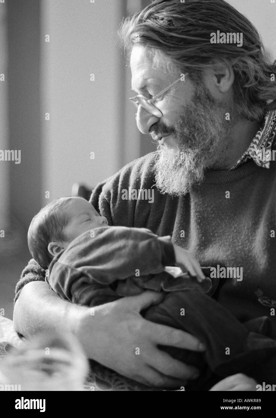 Mature man holding baby, side view, b&w Banque D'Images