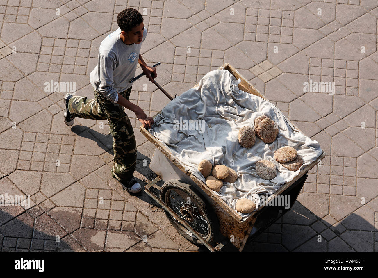 Jeune homme poussant panier chargé avec des pains plats, Place Djemaa el Fna, Marrakech, Maroc, Afrique Banque D'Images