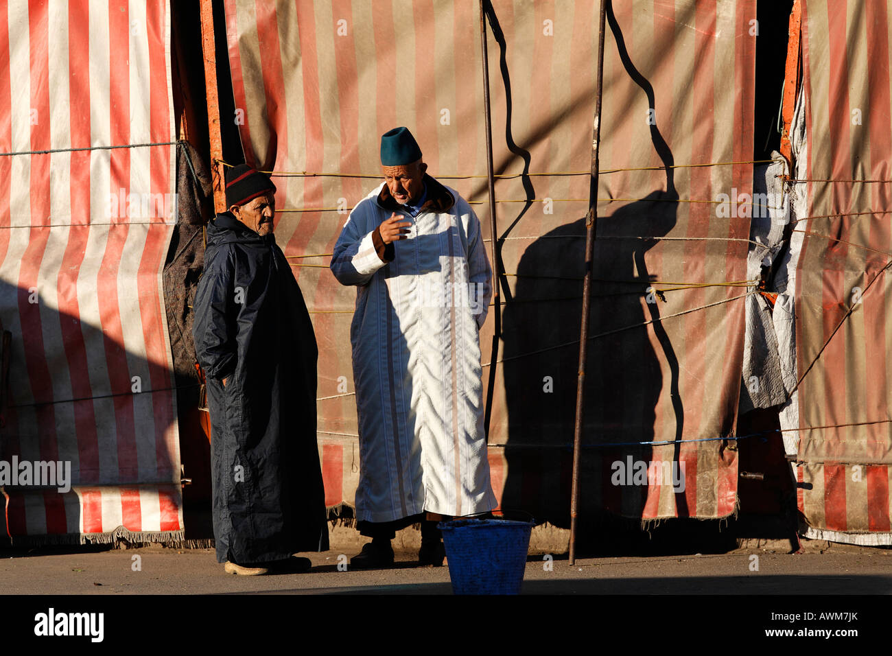 Deux vieux hommes marocains discutent dans la matin devant les étals de marché fermé, Marrakech, Maroc, Afrique Banque D'Images