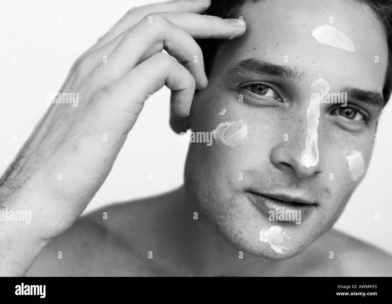 Homme avec dabs de crème hydratante sur le visage, portrait, b&w Banque D'Images