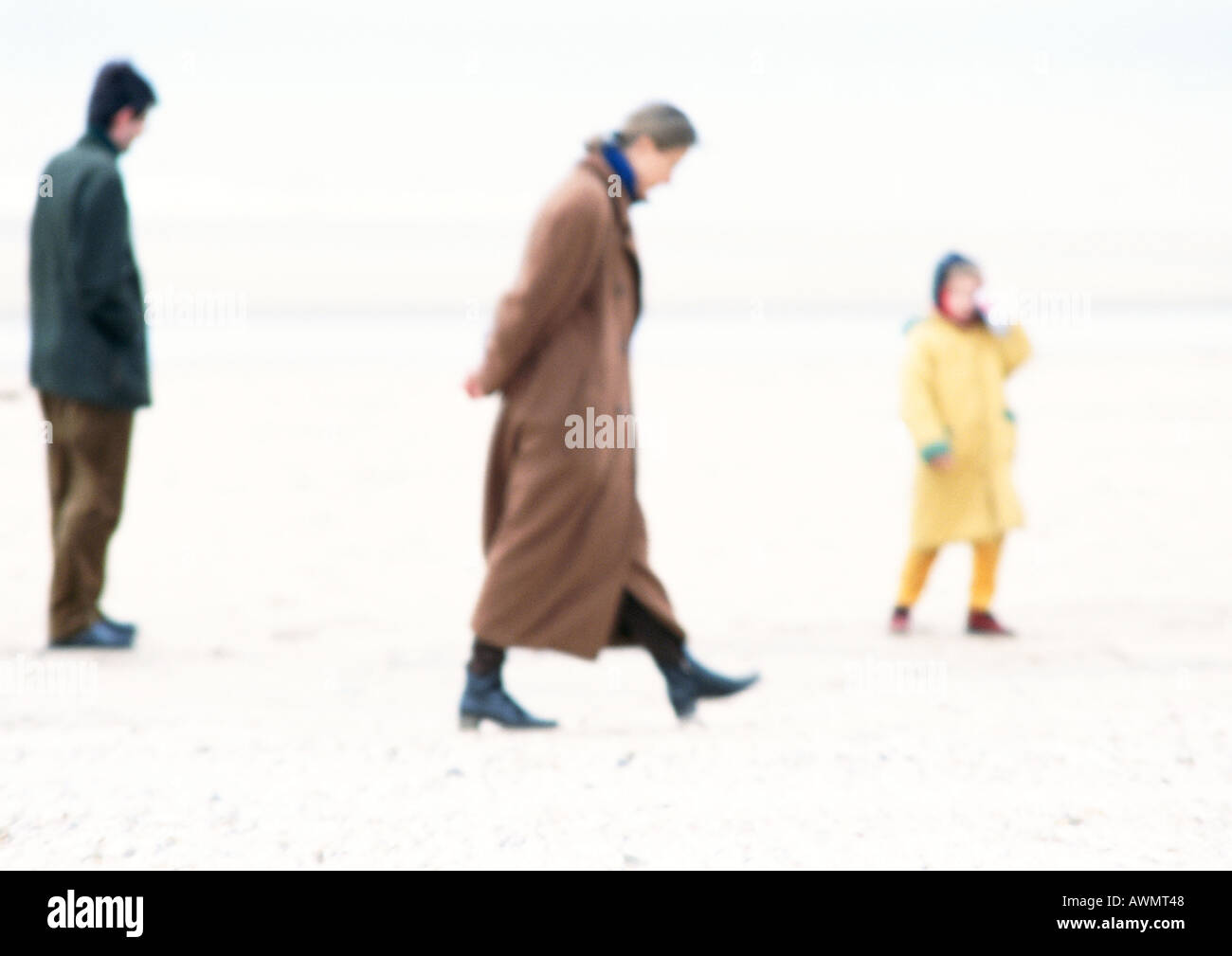 Les gens en manteaux walking on beach, blurred Banque D'Images