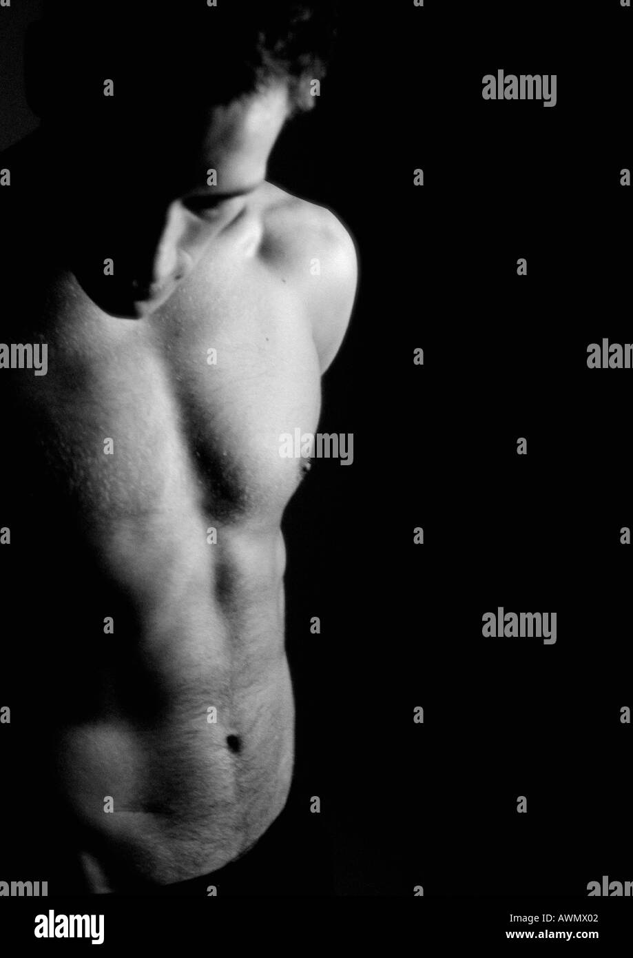 Nude man looking down, vue partielle, jusqu'à la taille, noir et blanc. Banque D'Images