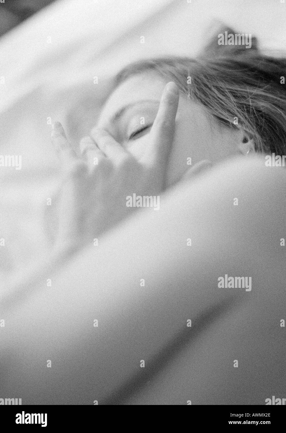 Woman lying on bed, close-up, noir et blanc Banque D'Images