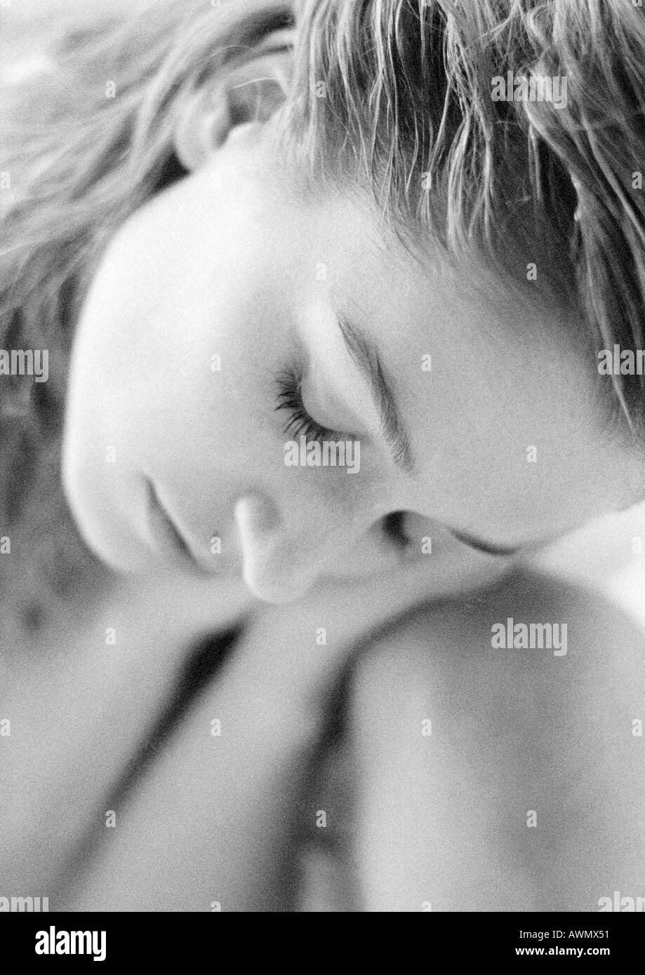 Femme avec les yeux fermés la tête penchée sur le genou, portrait, noir et blanc Banque D'Images