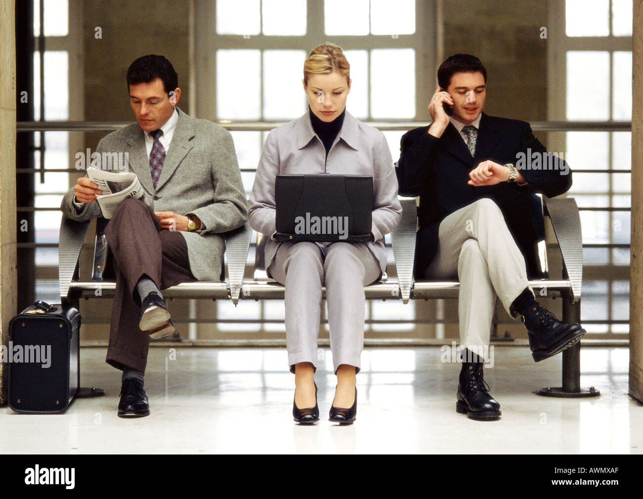 Businesswoman using laptop sitting entre deux hommes d'affaires. Banque D'Images