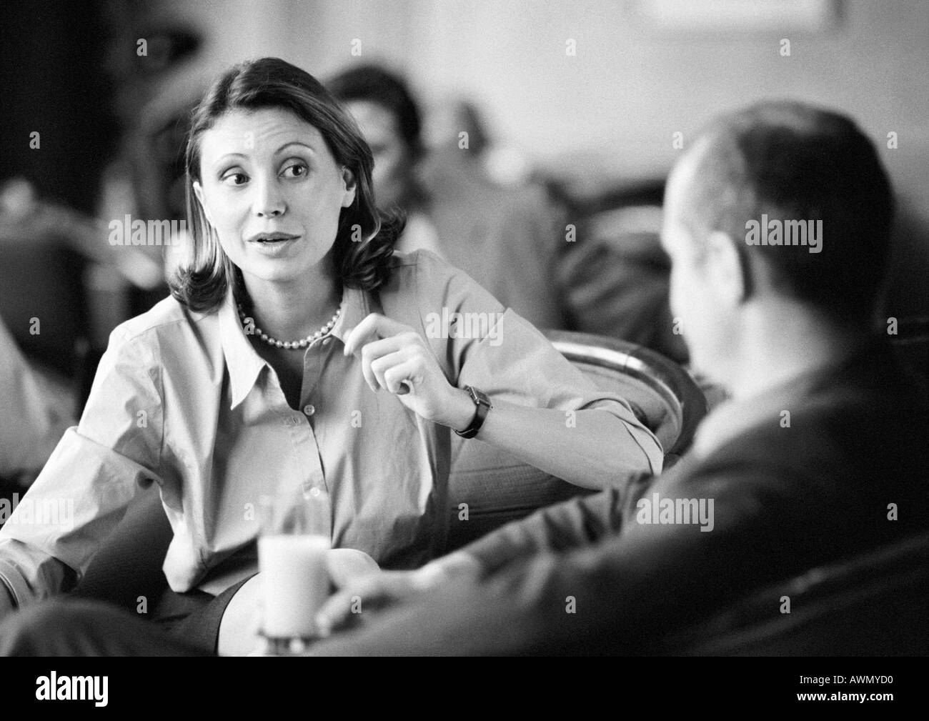 Businessman and businesswoman sitting together, parler, b&w. Banque D'Images