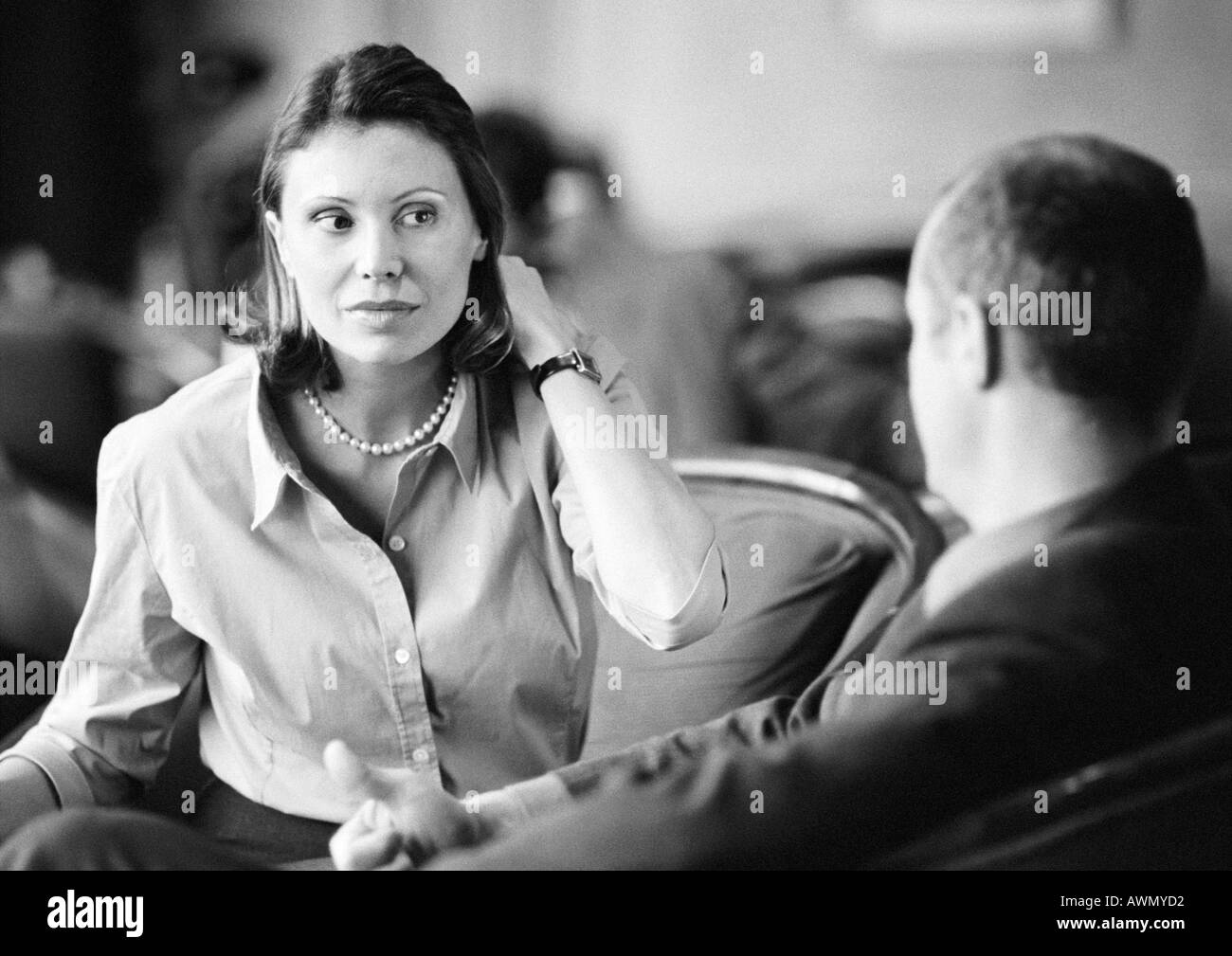 Businessman and businesswoman sitting together, parler, b&w. Banque D'Images