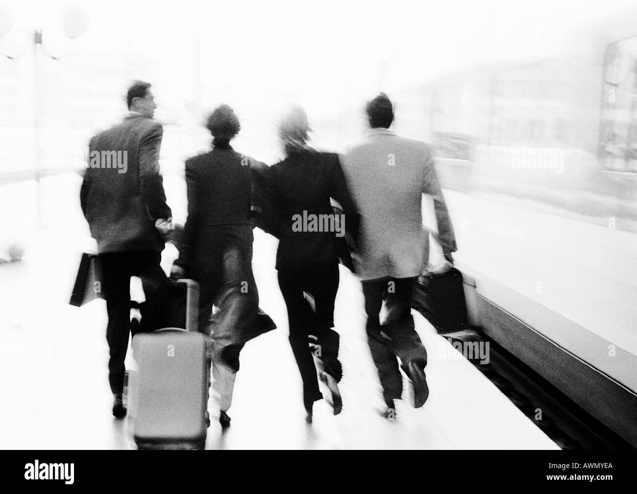 Groupe de gens d'affaires se dépêchant sur plate-forme du train, vue arrière, floue, b&w. Banque D'Images