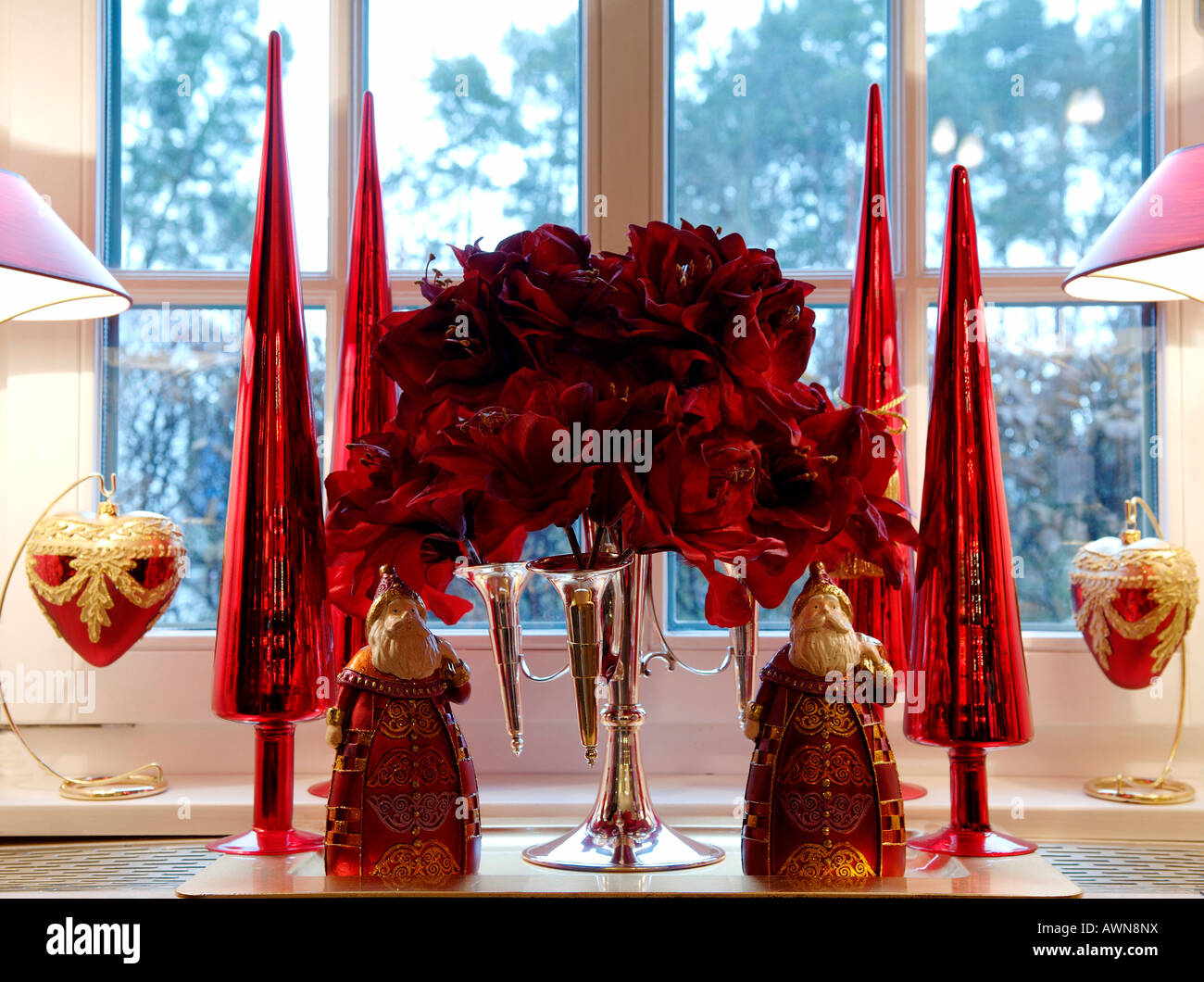 Les décorations de Noël devant une fenêtre, deux arbres de Noël stylisé Santas, rouge fleurs artificielles dans un quatre-armé candela Banque D'Images