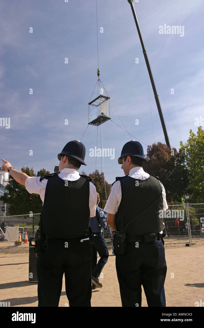 Un policier deux directions de pointage en vertu de l'article David Blane en suspension dans une boîte de plexiglass par Tower Bridge Londres Banque D'Images