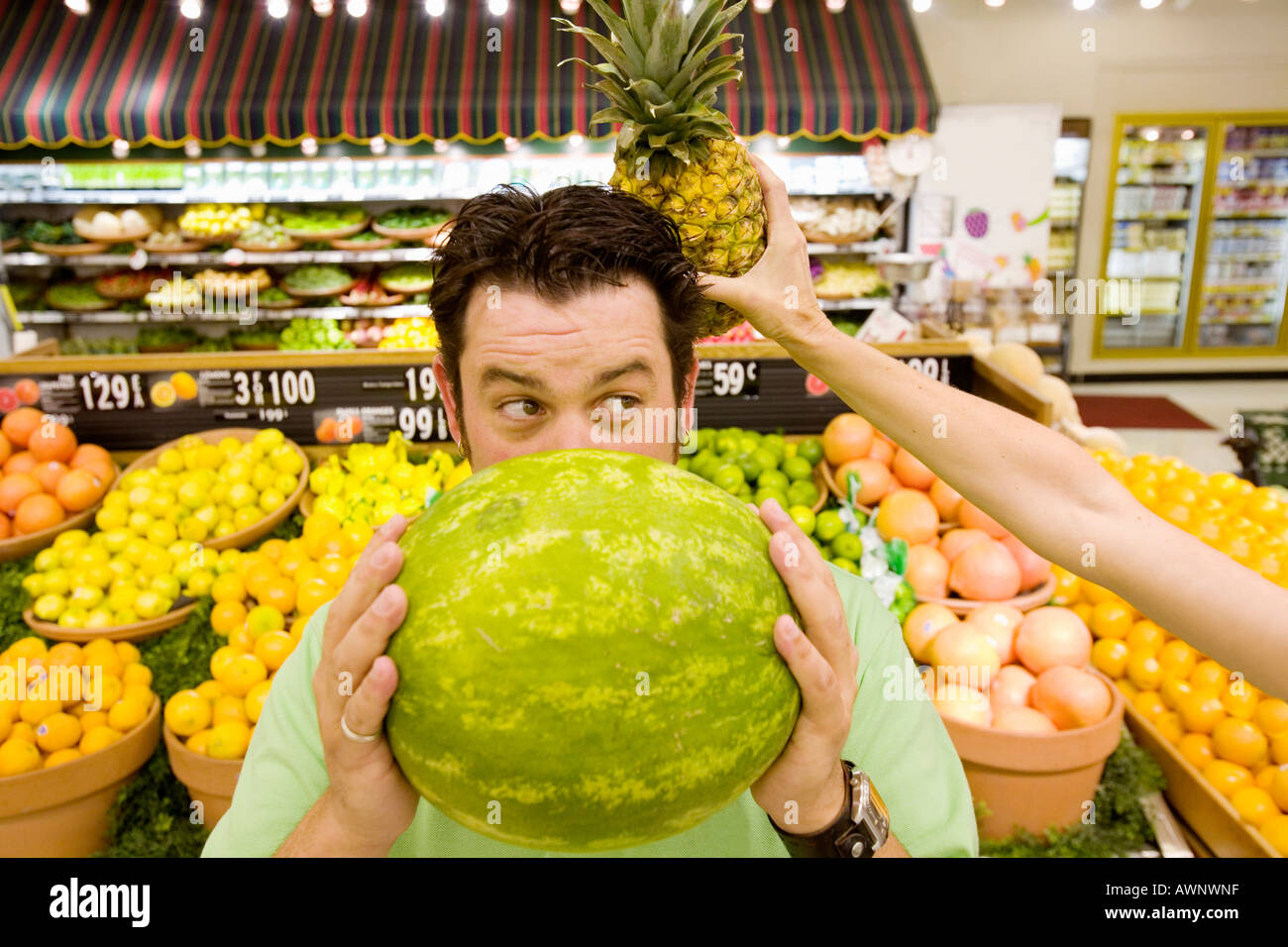 Man holding watermelon en supermarché comme femme derrière sa tête d'ananas Banque D'Images Man holding watermelon en supermarché comme femme derrière sa tête d'ananas Banque D'Images