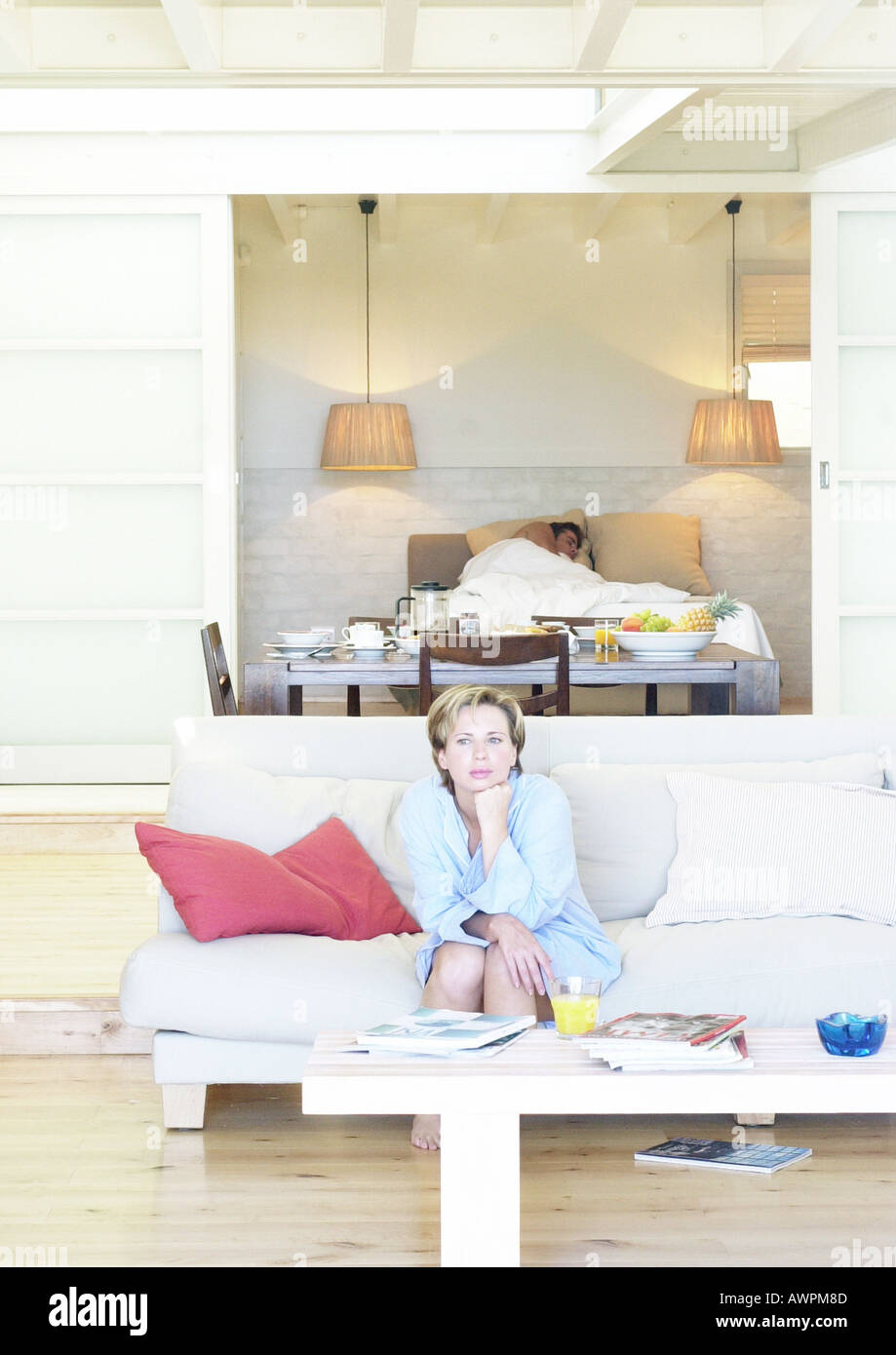 Femme assise sur un canapé, l'homme au lit en arrière-plan Banque D'Images