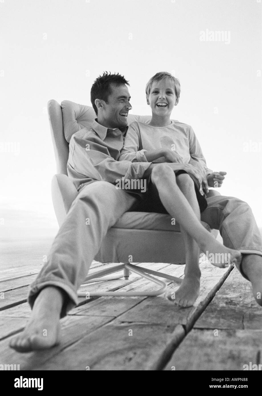 Père et fils assis dans un fauteuil, low angle view, b&w, portrait Banque D'Images