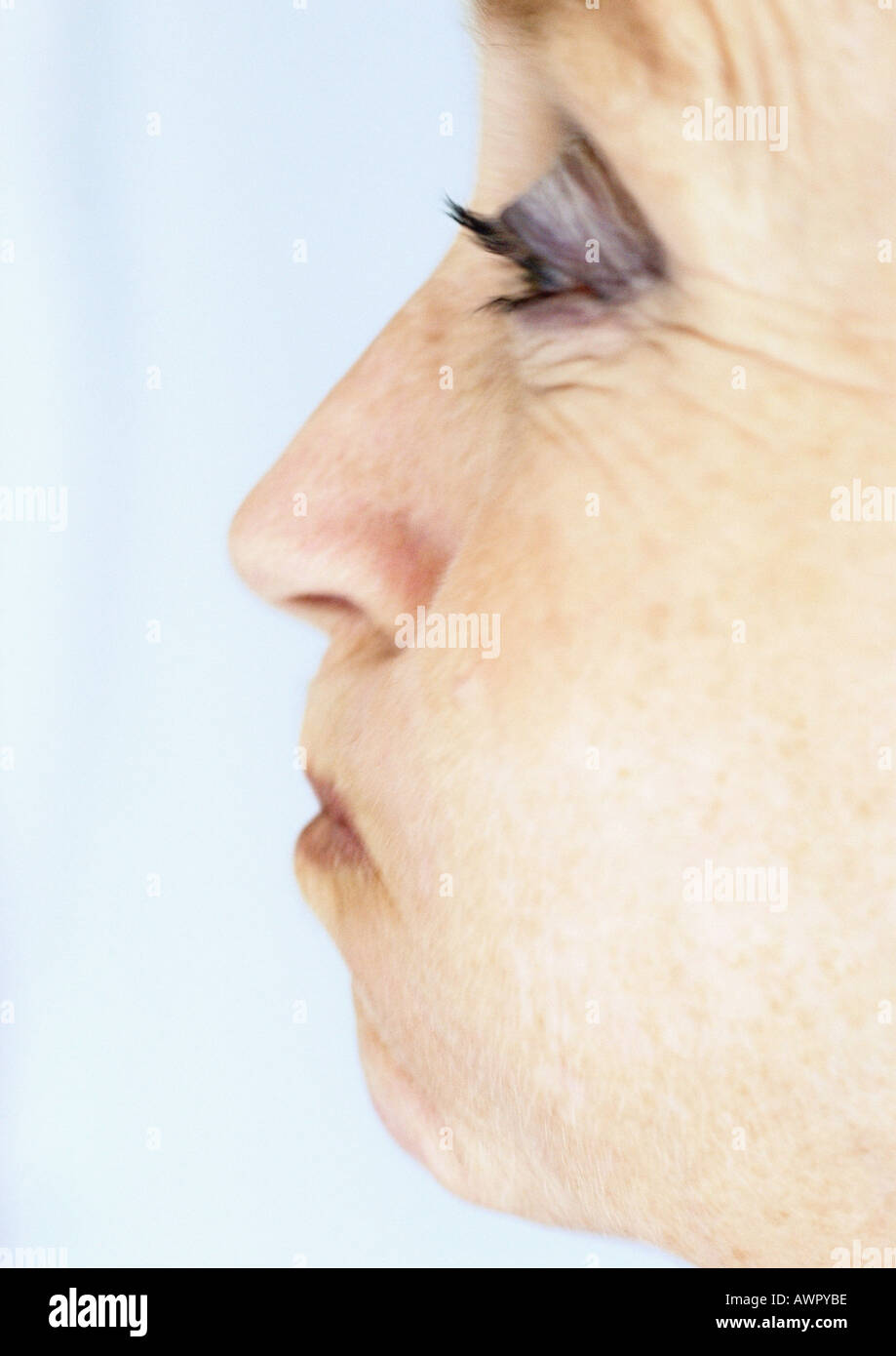 Femme mature puffing out joues, close-up, side view Banque D'Images