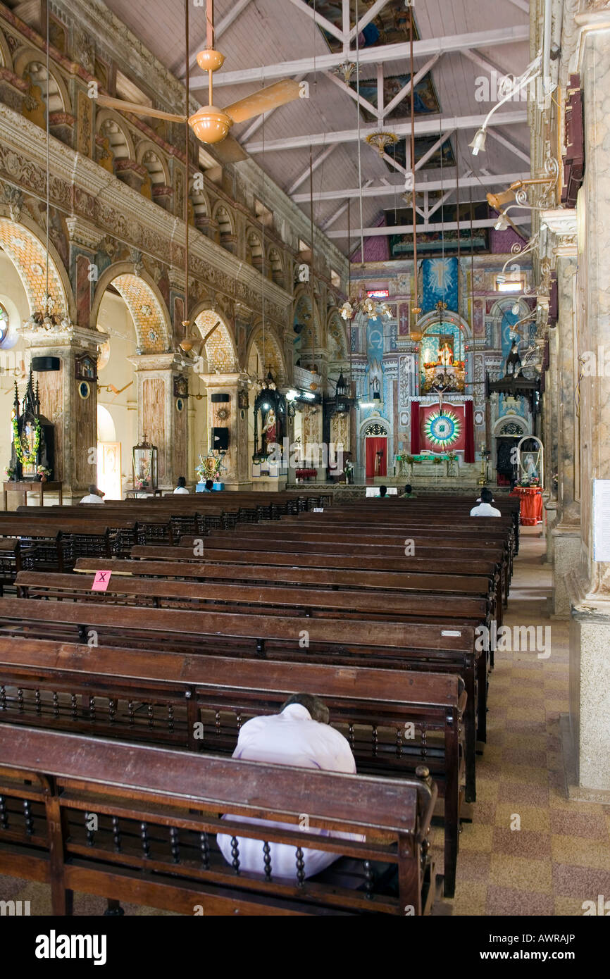 Les croyants solitaire avec révérence priant dans la nef de ornate Basilique Santa Cruz. Fort Kochi, fort Cochin, Kerala, Inde du Sud Banque D'Images