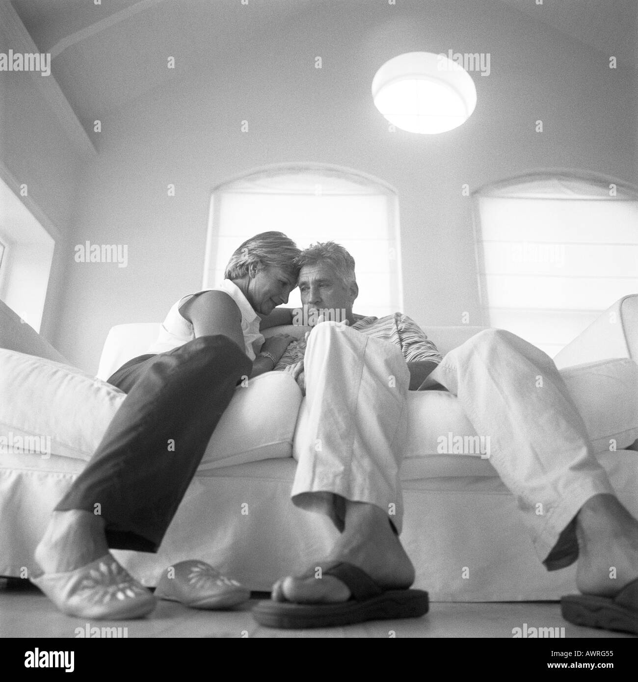 Young couple sitting on sofa, low angle view, b&w Banque D'Images