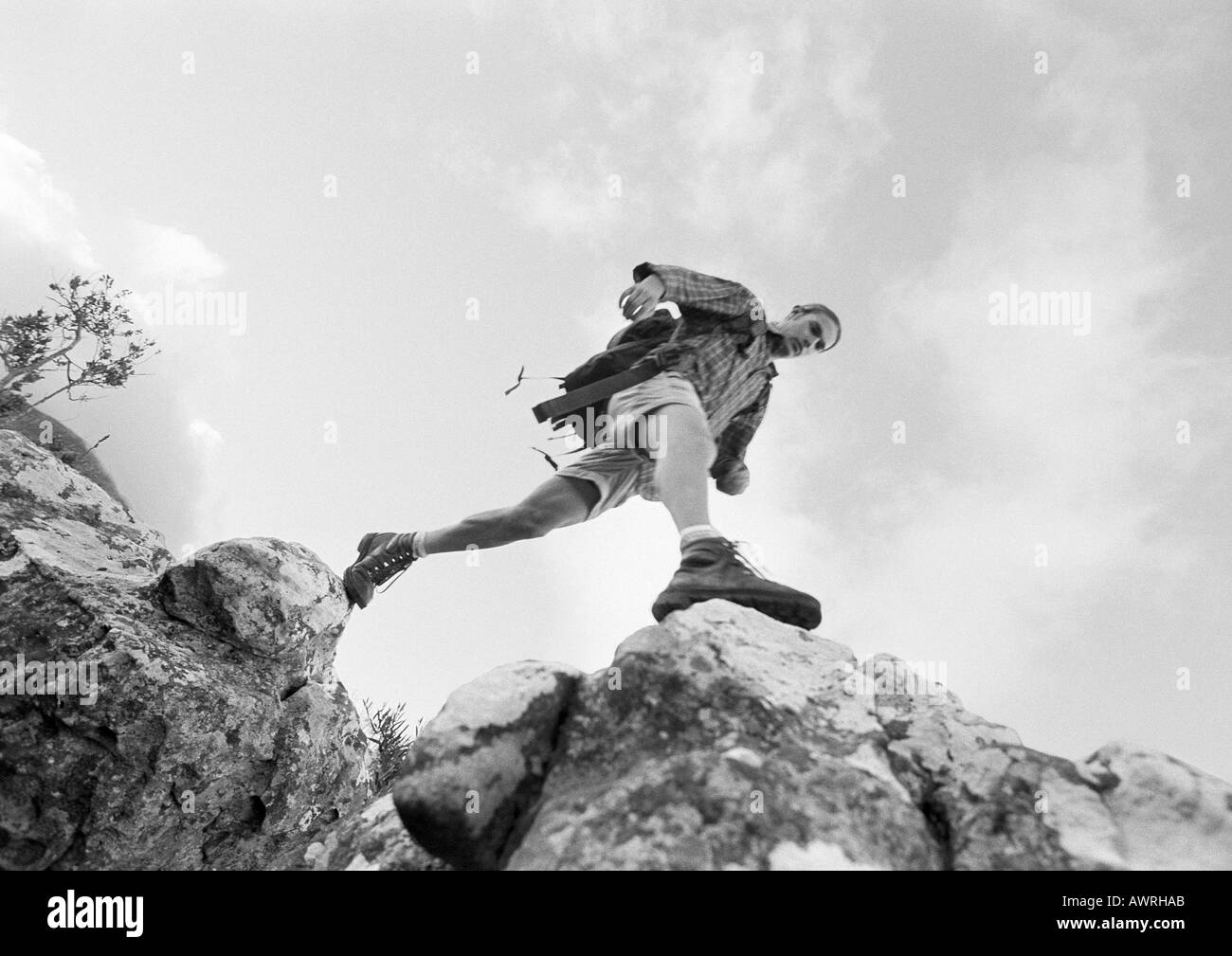 L'homme en franchissant les roches, low angle view, b&w. Banque D'Images