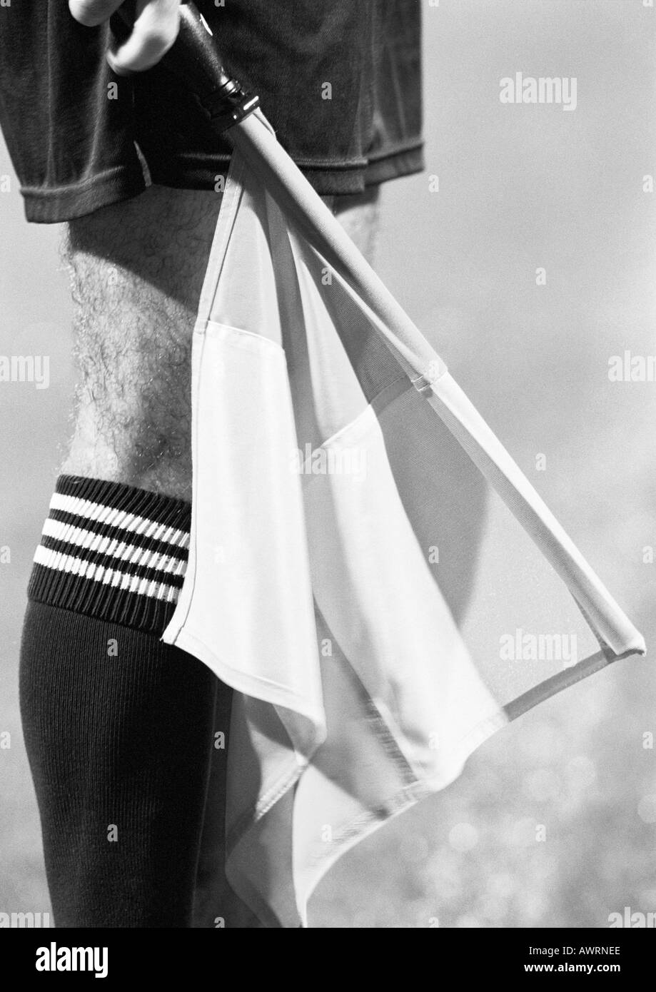 Juge de ligne en match de foot holding drapeau, close-up de jambe et d'un drapeau, b&w. Banque D'Images