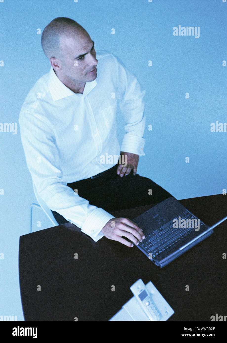 Businessman sitting at desk with laptop computer, high angle view Banque D'Images