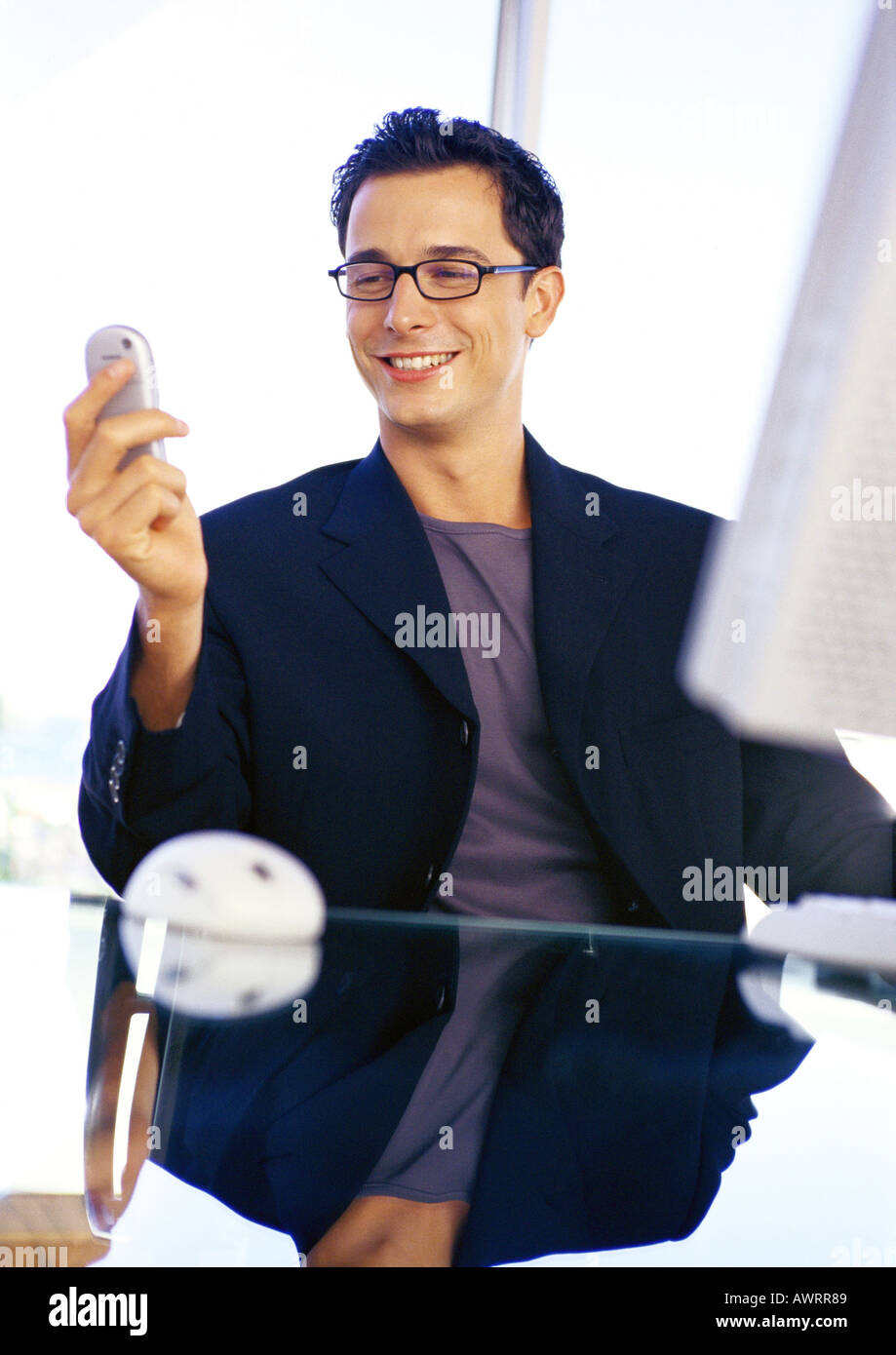 Businessman holding cell phone, smiling Banque D'Images