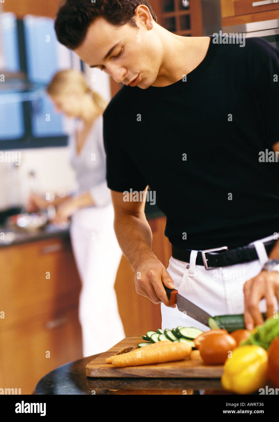 Man slicing vegetables in kitchen, mi-section Banque D'Images