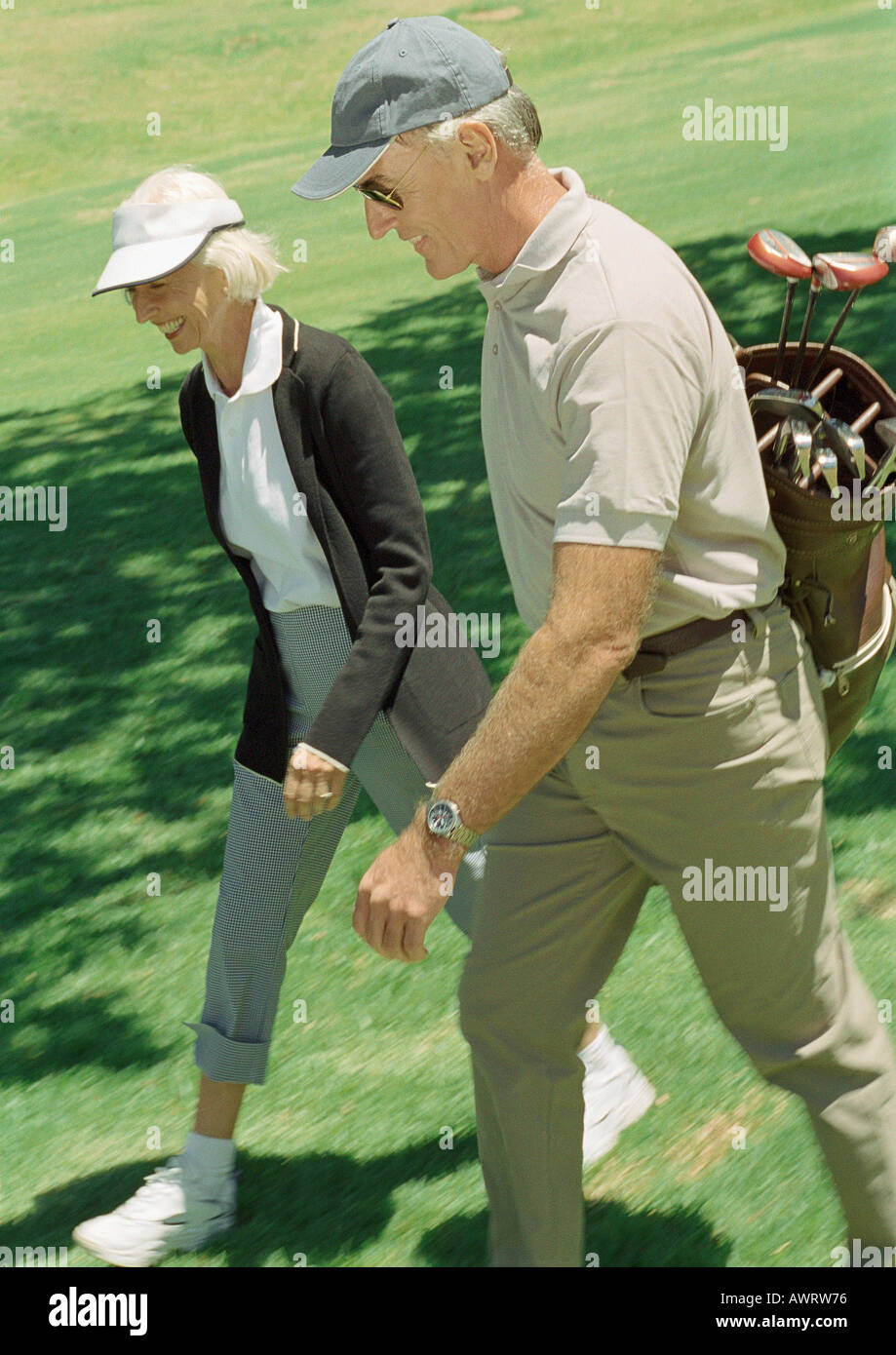 Man and woman on green, man carrying golf clubs Banque D'Images