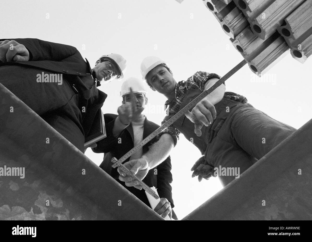 Trois hommes à la règle lors du pliage, low angle view, b&w Banque D'Images