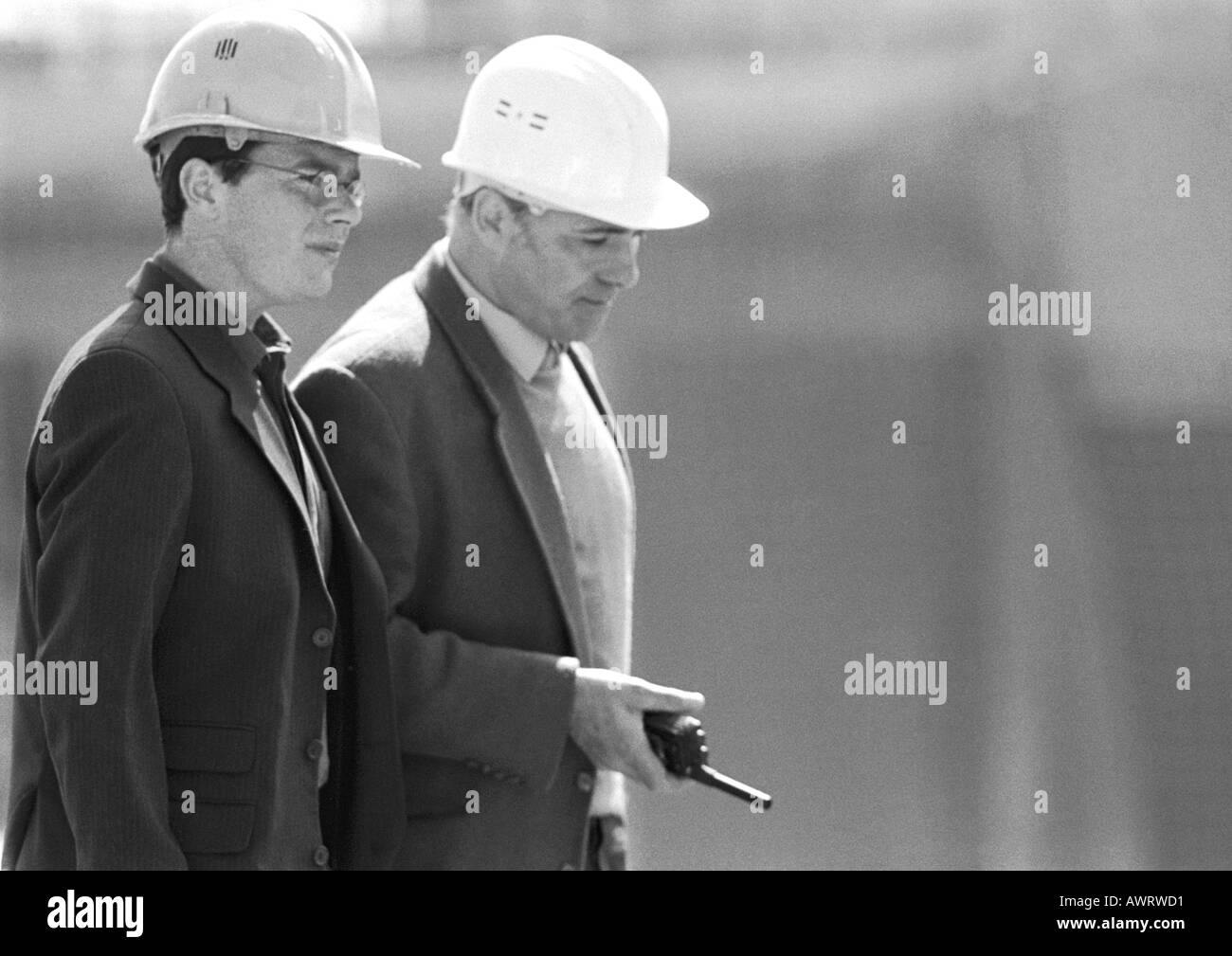 Deux hommes avec des casques, un holding talkie-walkie,taille, vue latérale, b&w Banque D'Images