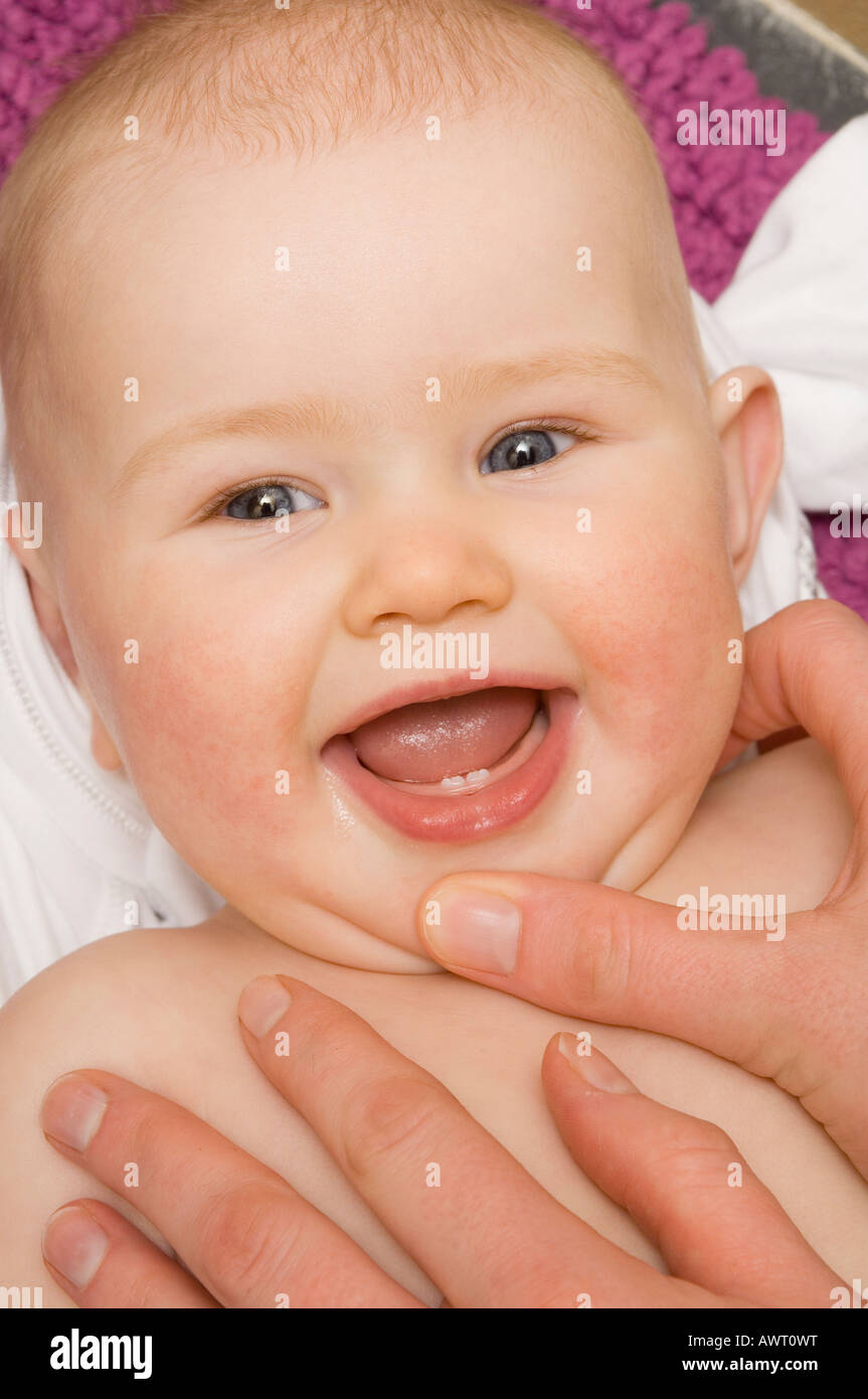 Mère exhibant son bébé de 6 mois bébé fille montrant premières dents Banque D'Images