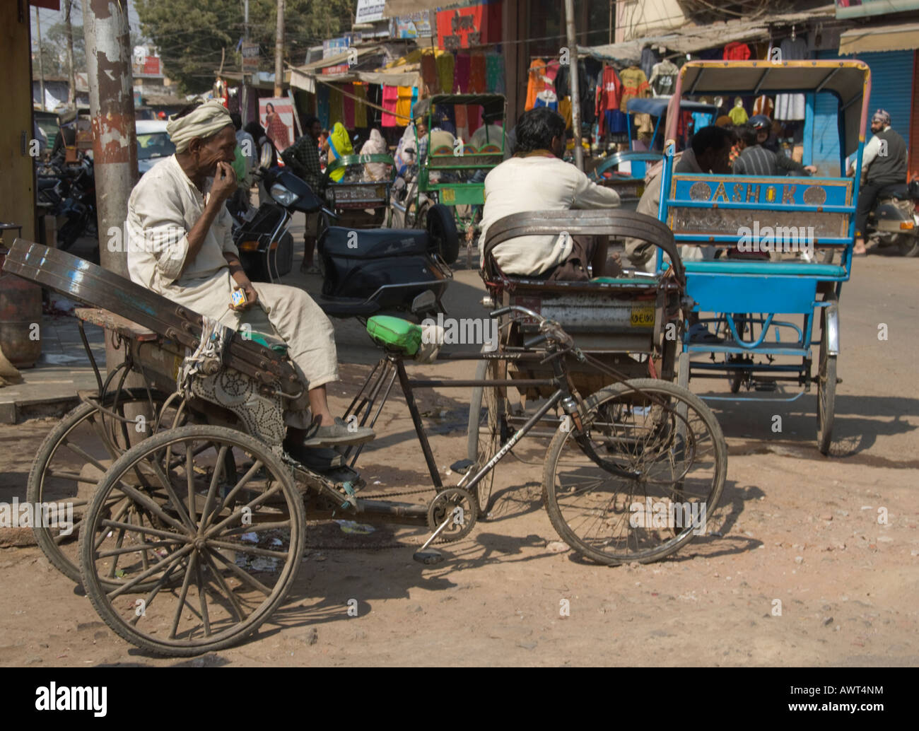 Rickshaw ou pedicab driver attendent des passagers sur une rue animée dans le centre du marché de l'Agra, Inde. Banque D'Images