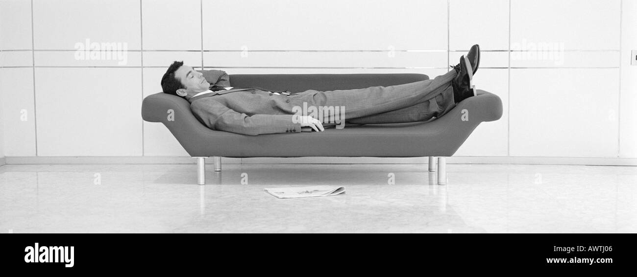 Businessman taking sieste sur canapé b&w, vue panoramique Banque D'Images