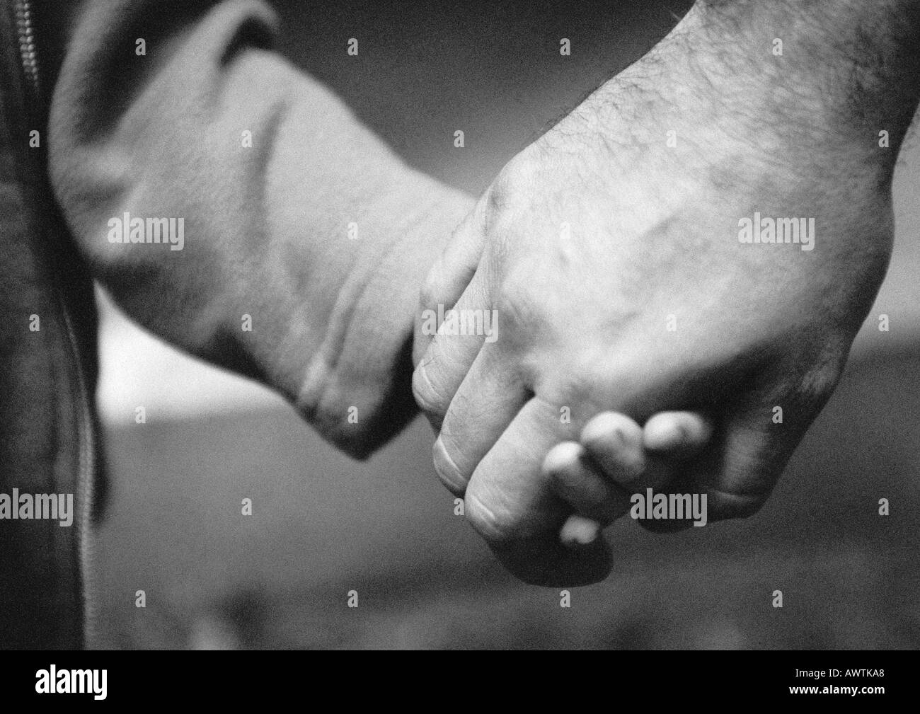 Mains adultes tenant la main de l'enfant, close-up, b&w Banque D'Images