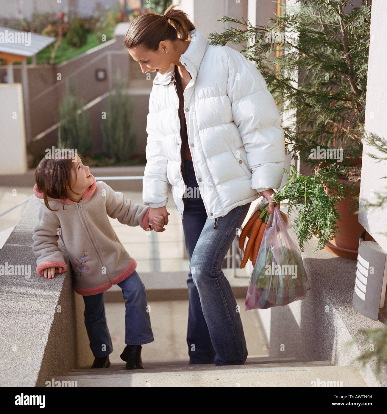 Mother holding daughter's hand, en montant un escalier Banque D'Images