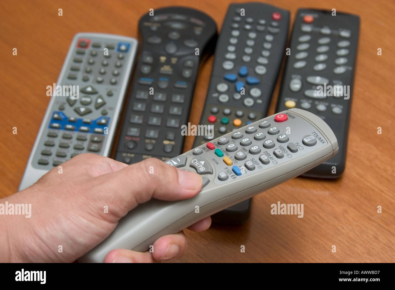 Main tenant la télécommande entre de nombreux contrôles à distance concept confusion choix complexité Banque D'Images