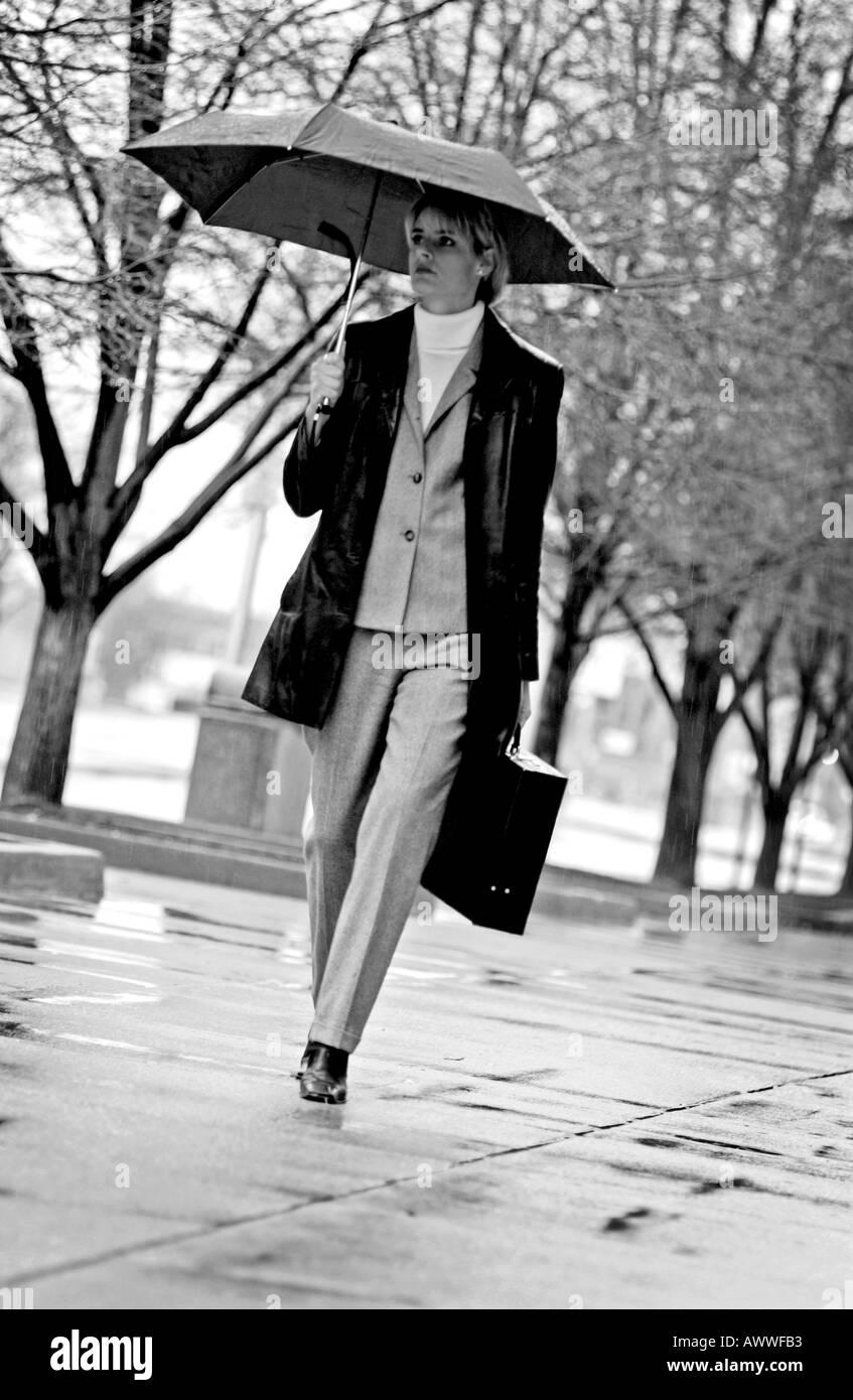 Businesswoman walking in the rain Banque D'Images