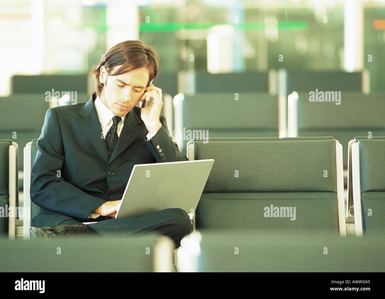 Businessman using laptop in airport lounge Banque D'Images