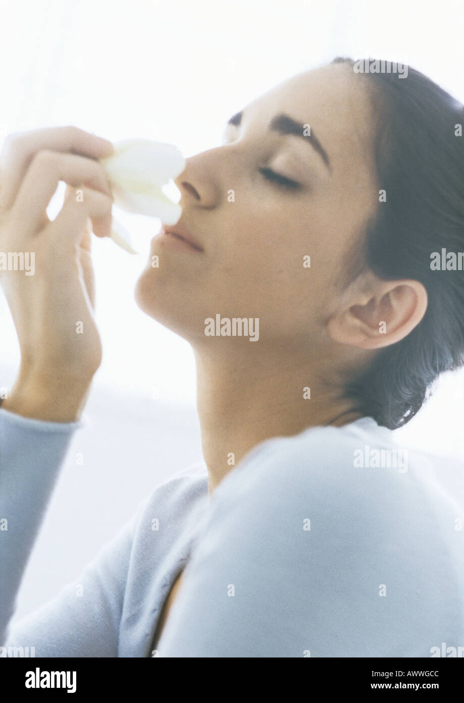 Woman smelling flower, les yeux fermés Banque D'Images