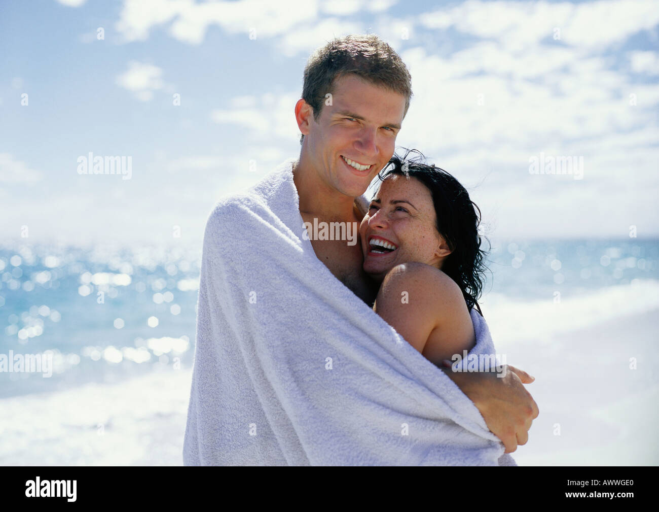 Couple embracing at beach, enveloppé dans une serviette, portrait Banque D'Images