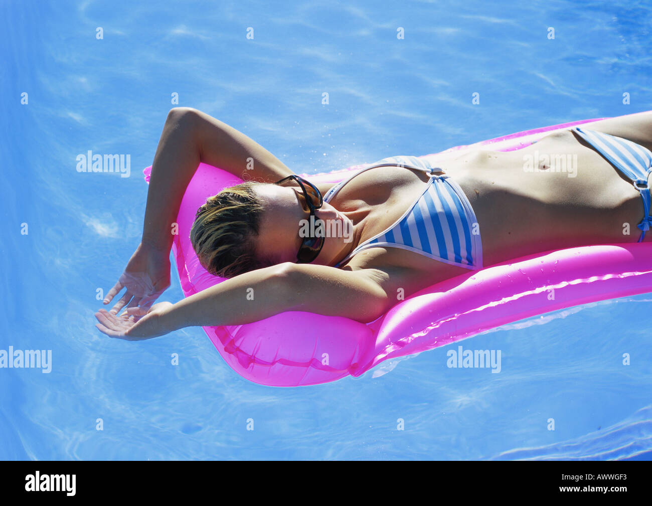 Femme allongée sur un matelas pneumatique dans la piscine Banque D'Images