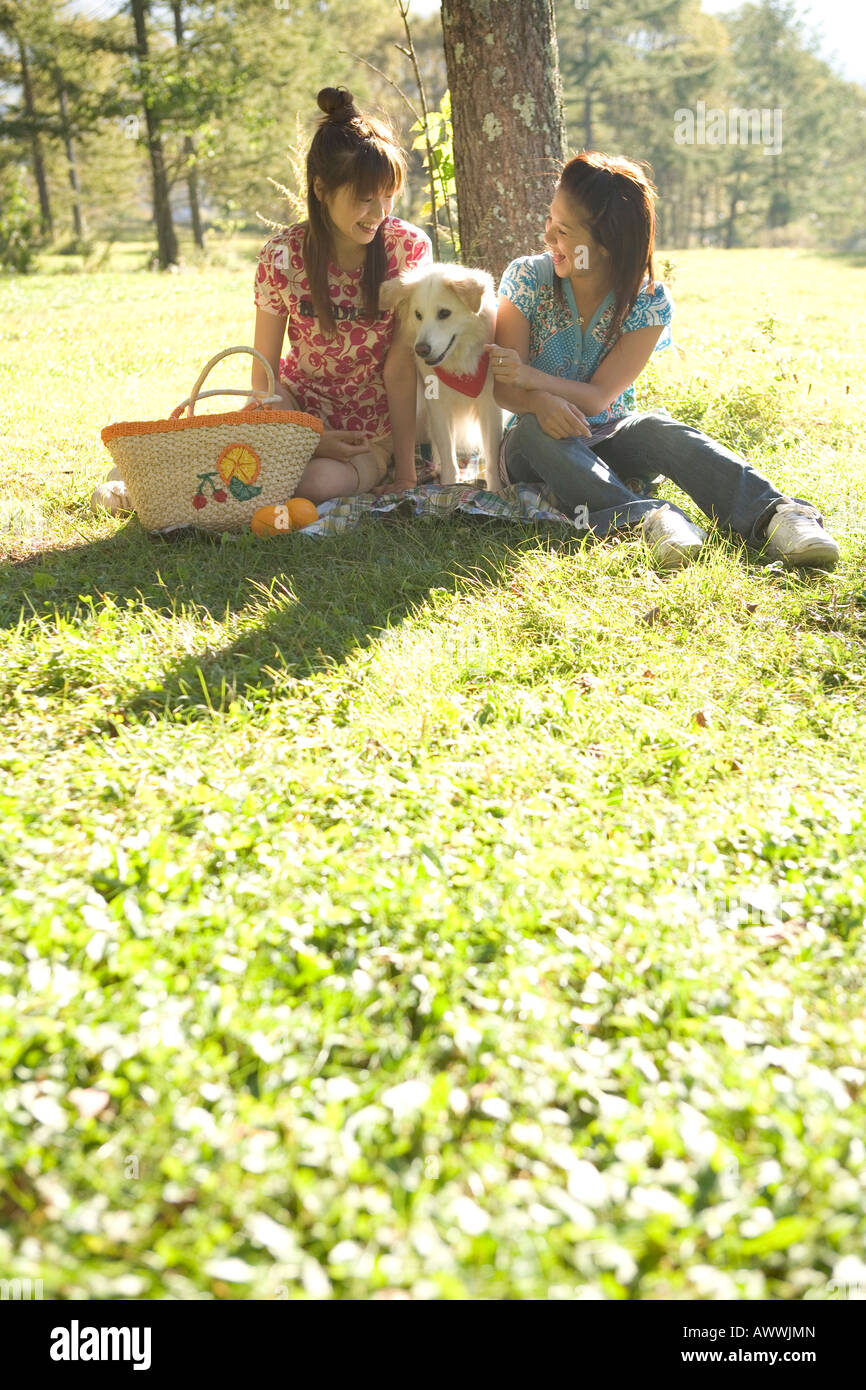 Deux femmes avec dog having picnic in park Banque D'Images