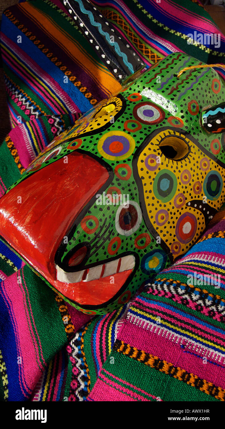 Masque de danse en bois guatémaltèque contre un marché textile multicolores, Chichicastenango, Guatemala Banque D'Images