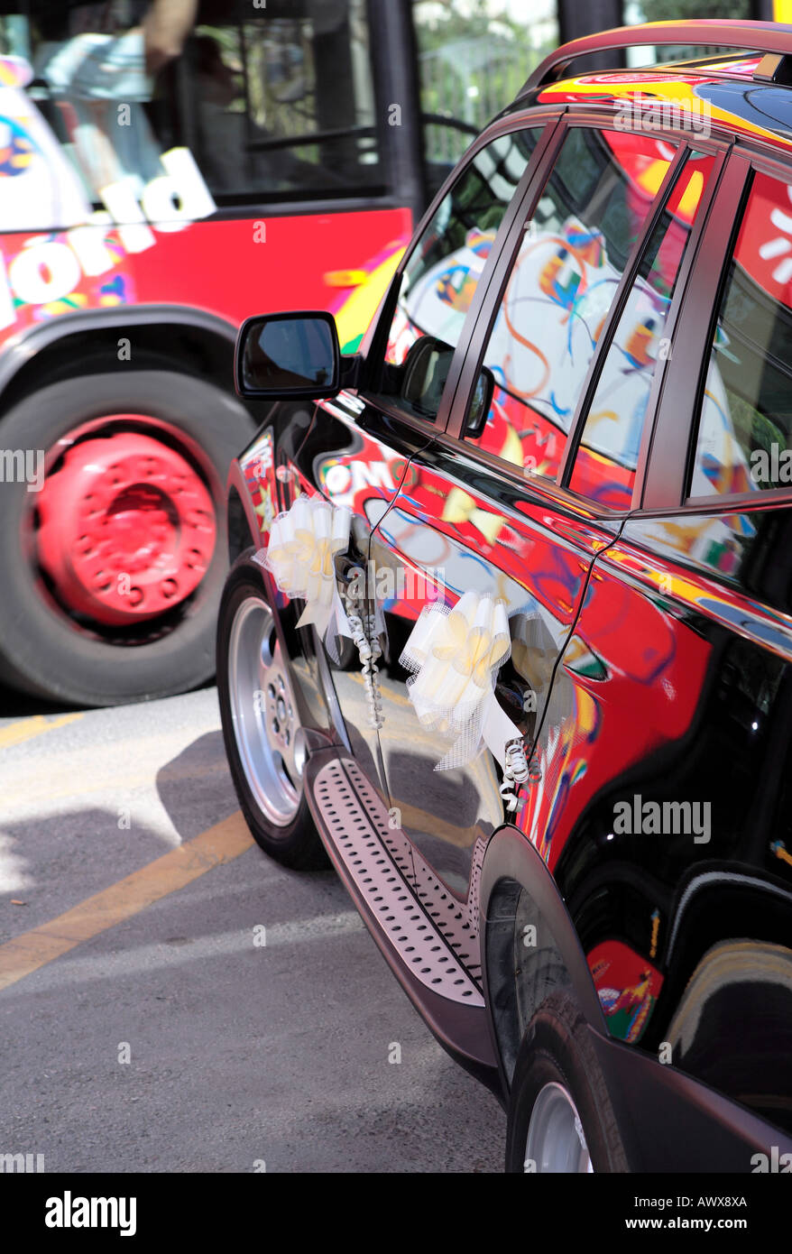 Bus coloré passant de voiture de mariage noir avec des rubans et des réflexions dans la peinture Banque D'Images