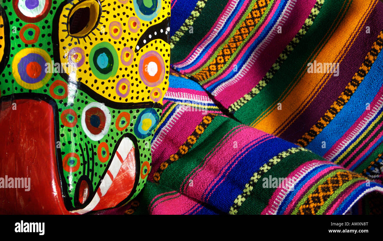 Détail d'un masque de danse en bois guatémaltèque contre un marché textile multicolores, Chichicastenango, Guatemala Banque D'Images